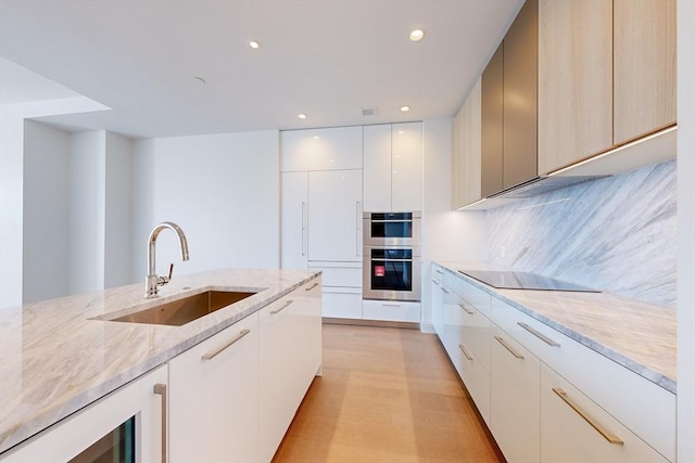 kitchen featuring sink, black electric stovetop, tasteful backsplash, light stone countertops, and stainless steel double oven