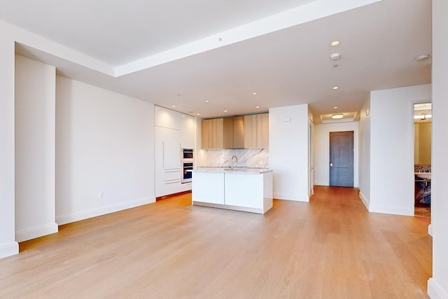 unfurnished living room featuring sink and light wood-type flooring