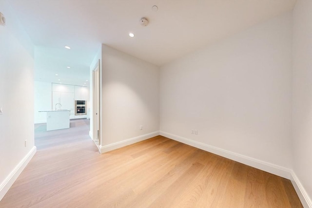 unfurnished room featuring sink and light hardwood / wood-style flooring