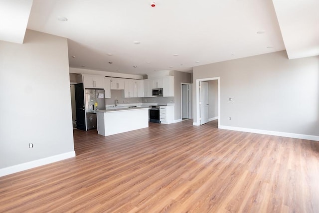 unfurnished living room featuring sink and hardwood / wood-style floors