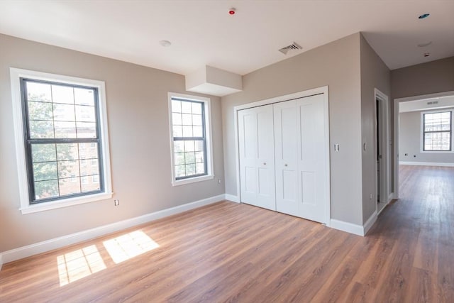 unfurnished bedroom with dark hardwood / wood-style flooring, a closet, and multiple windows