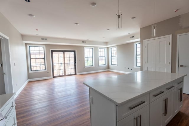 kitchen featuring plenty of natural light, a center island, light stone countertops, and hardwood / wood-style flooring