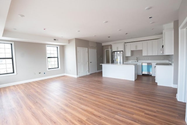 kitchen featuring appliances with stainless steel finishes, wood-type flooring, a center island, and white cabinets