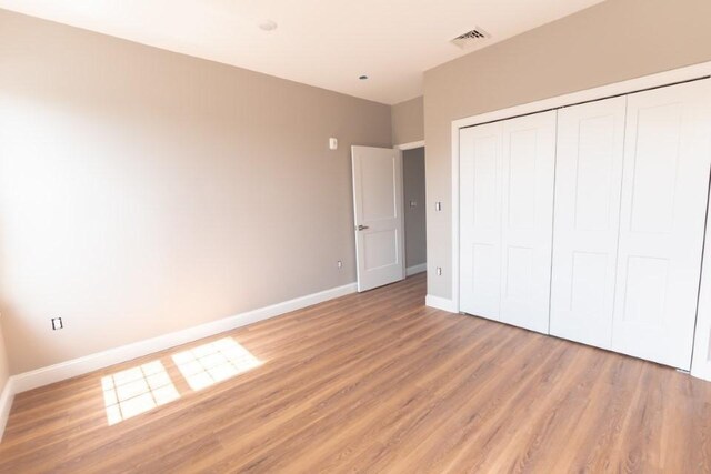 unfurnished bedroom with light wood-type flooring and a closet