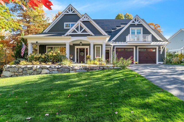 view of front of property with solar panels, a front lawn, a balcony, and driveway
