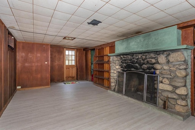 below grade area with wood finished floors, wooden walls, and a stone fireplace