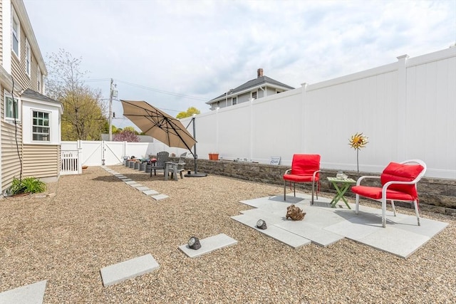 view of yard with a gate, a fenced backyard, and a patio area
