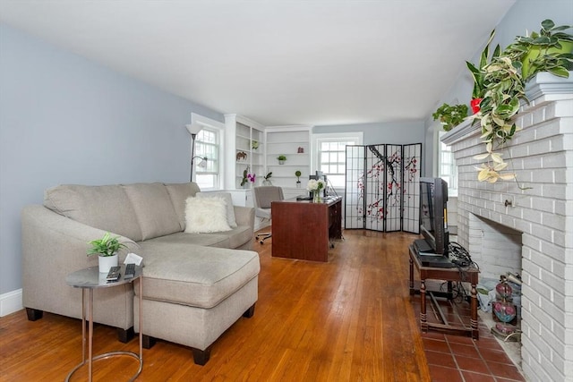 living area with wood finished floors and a brick fireplace