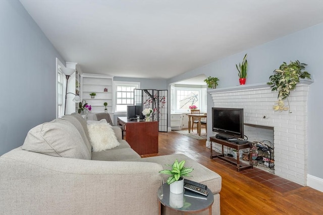 living area featuring wood finished floors and a brick fireplace