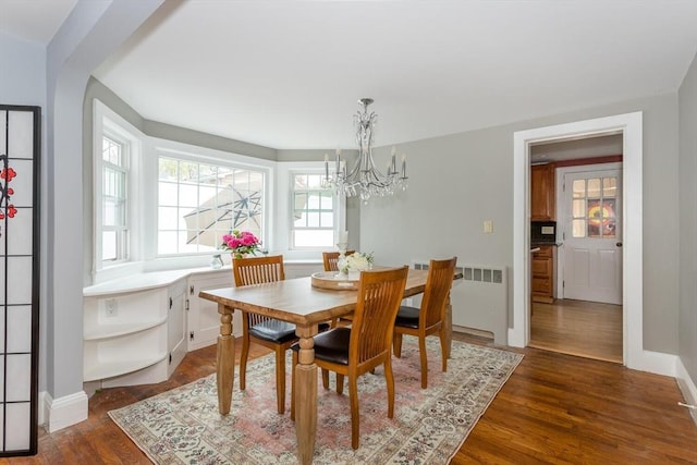 dining room featuring dark wood finished floors, arched walkways, a chandelier, radiator, and baseboards