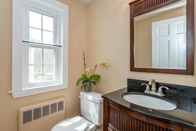 half bath featuring radiator, toilet, and vanity