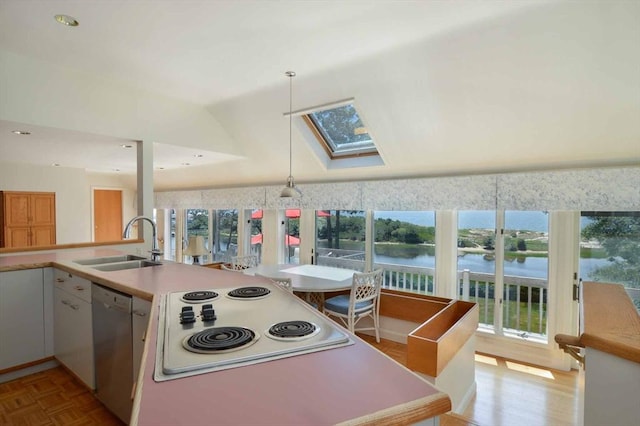 kitchen featuring white electric stovetop, dishwasher, sink, decorative light fixtures, and a water view