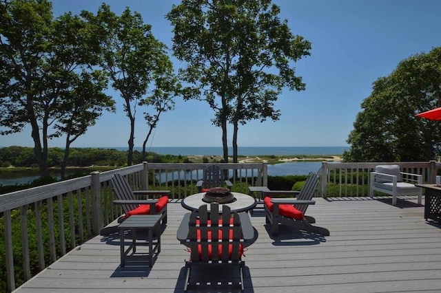 wooden deck with an outdoor fire pit and a water view