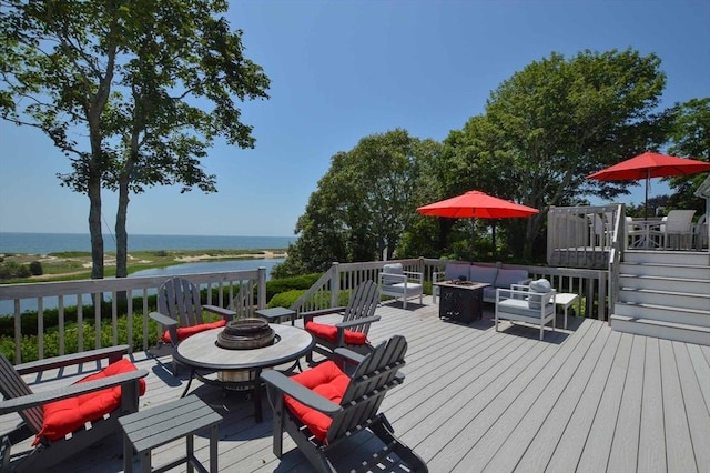 deck featuring a water view and an outdoor living space with a fire pit