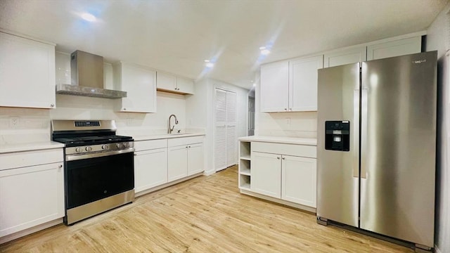 kitchen with wall chimney range hood, white cabinetry, appliances with stainless steel finishes, and light countertops