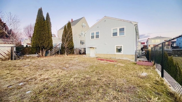 rear view of property with a fenced backyard and a lawn