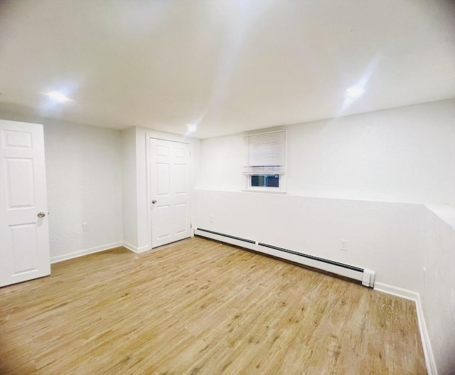 spare room with light wood-style floors, a baseboard radiator, and baseboards