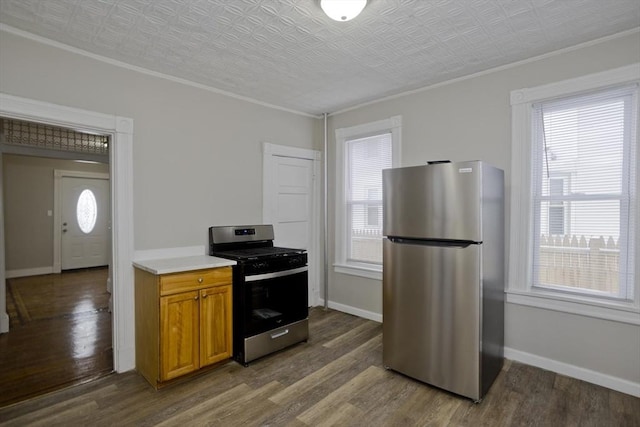 kitchen featuring dark wood-type flooring, a healthy amount of sunlight, stainless steel appliances, and ornamental molding