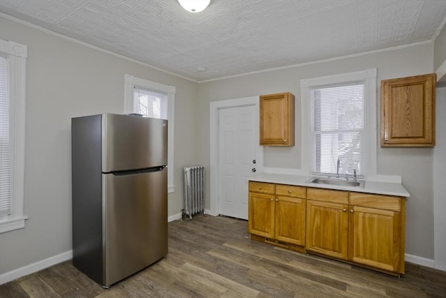 kitchen featuring sink, stainless steel refrigerator, radiator, a healthy amount of sunlight, and hardwood / wood-style floors