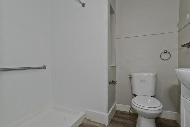 bathroom featuring vanity, a shower, hardwood / wood-style floors, and toilet