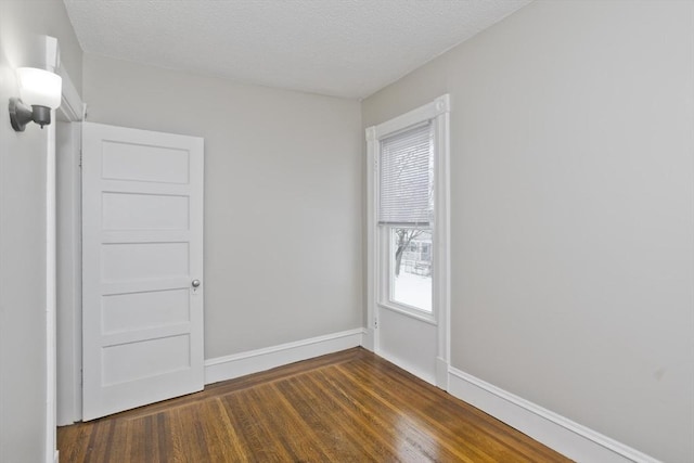 spare room with dark hardwood / wood-style floors and a textured ceiling