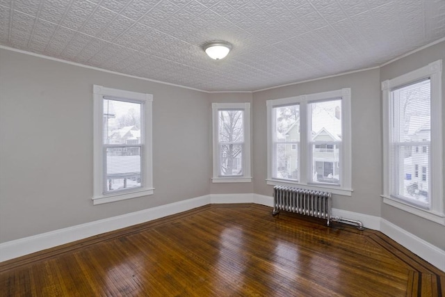 empty room featuring dark hardwood / wood-style flooring, radiator, and ornamental molding