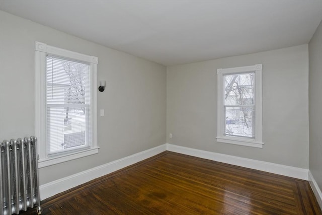 unfurnished room with radiator and dark wood-type flooring