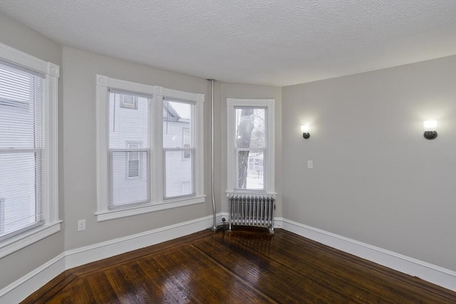 empty room featuring dark hardwood / wood-style flooring, radiator, and a textured ceiling