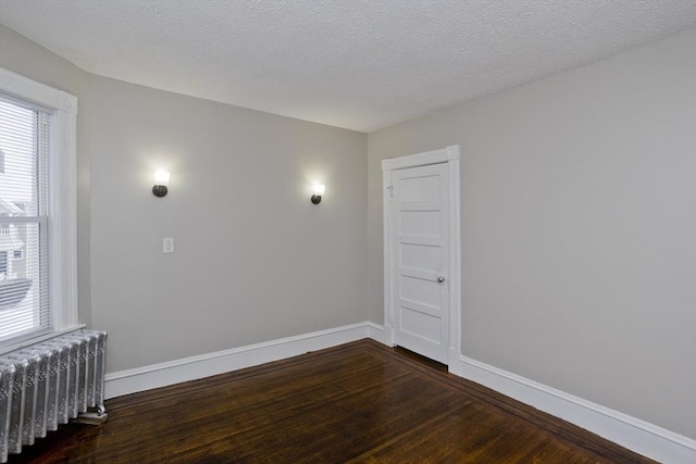 empty room with radiator, dark wood-type flooring, and a textured ceiling