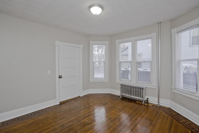 empty room with radiator heating unit and dark hardwood / wood-style floors