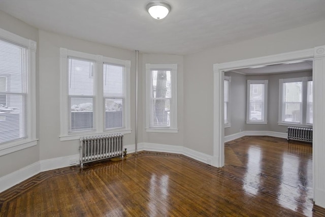 spare room with a healthy amount of sunlight, radiator heating unit, and dark hardwood / wood-style flooring