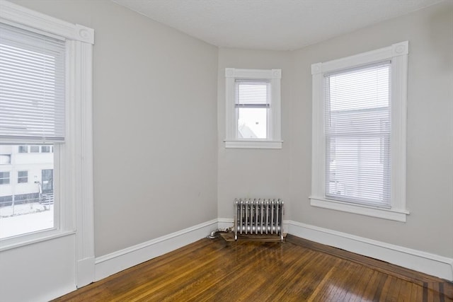 unfurnished room featuring radiator and dark hardwood / wood-style floors