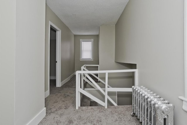 corridor with carpet flooring and a textured ceiling