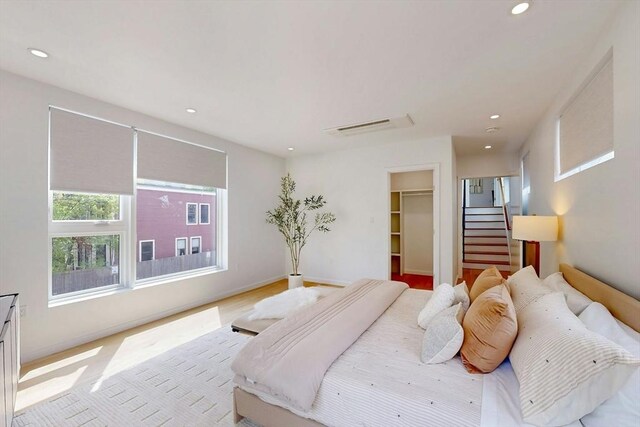 bedroom with recessed lighting, a walk in closet, and a closet