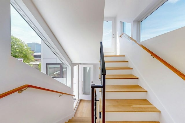 stairs with healthy amount of natural light and wood finished floors