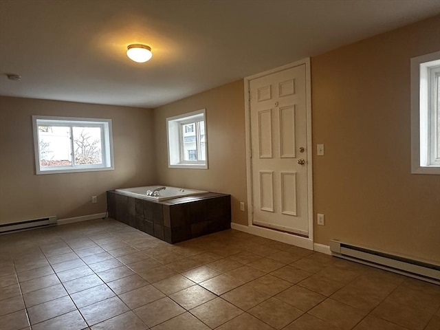 spare room featuring a baseboard radiator, light tile patterned flooring, and a healthy amount of sunlight