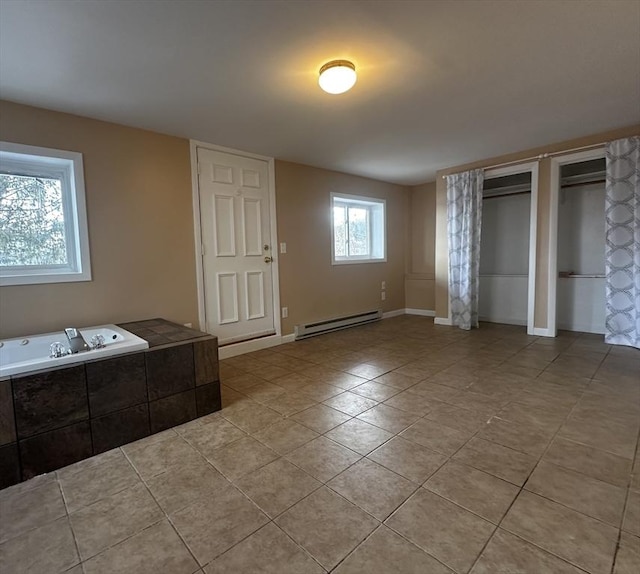 interior space featuring baseboard heating, light tile patterned flooring, and multiple windows