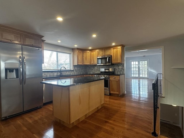 kitchen with stainless steel appliances, a center island, a healthy amount of sunlight, and dark hardwood / wood-style floors