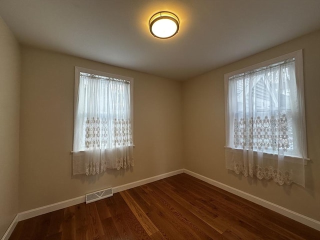 unfurnished room with plenty of natural light and dark hardwood / wood-style floors