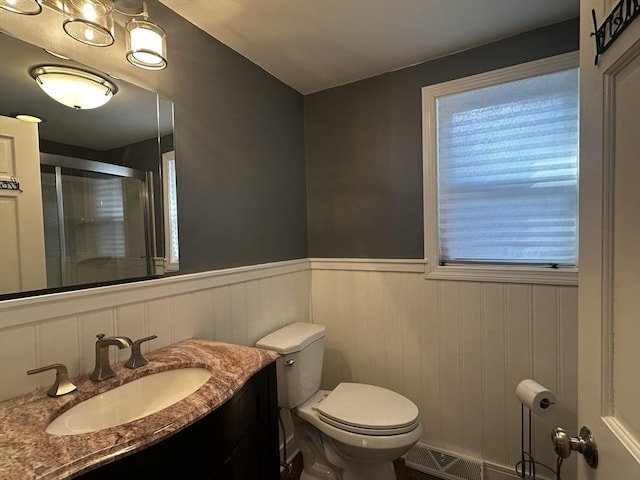 bathroom featuring toilet, walk in shower, and vanity