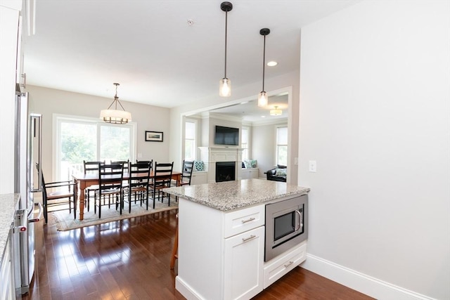 50 Brookview Rd Unit 50, Franklin, MA 02038 - kitchen featuring stainless steel microwave, a fireplace, white cabinets, light stone counters, and dark wood finished floors