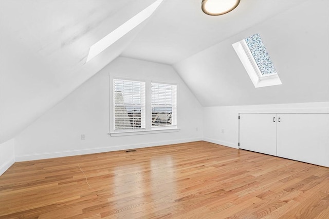 bonus room with light hardwood / wood-style floors and vaulted ceiling with skylight