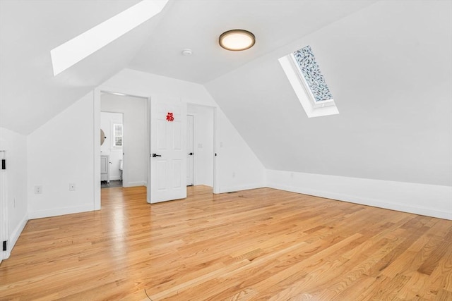 bonus room with lofted ceiling with skylight and light hardwood / wood-style floors