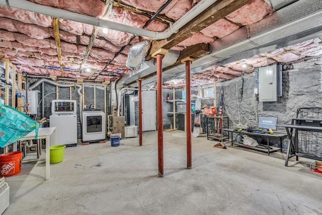 basement with heating unit, electric panel, water heater, and washing machine and dryer