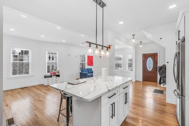 kitchen with white cabinetry, stainless steel fridge, a center island, and pendant lighting