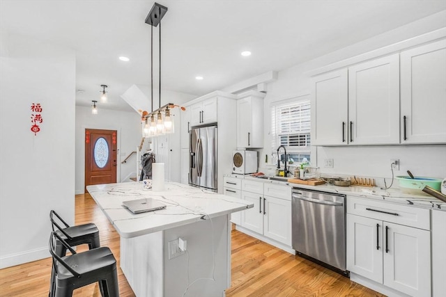 kitchen featuring sink, decorative light fixtures, a center island, stainless steel appliances, and white cabinets