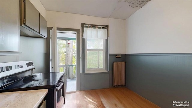 48 Summer St, Adams, MA 01220 - kitchen with stainless steel electric range oven, radiator heating unit, light wood finished floors, and a wainscoted wall