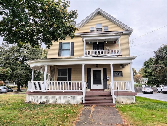view of front of house with a porch, a balcony, and a front yard