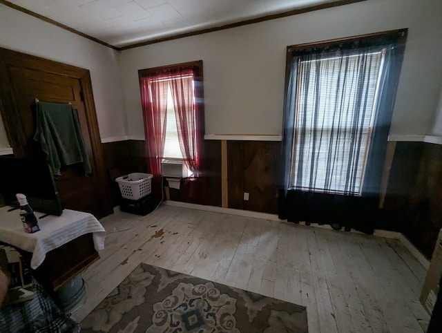 interior space featuring wooden walls, ornamental molding, and light wood-type flooring