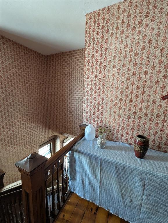 interior space featuring an upstairs landing, hardwood / wood-style floors, and wallpapered walls